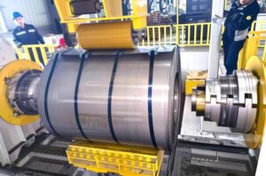MRISECNC automatic decoiling solution showing a metal coil loaded on the expanding mandrel of a REEGAO coil-fed laser blanking line.